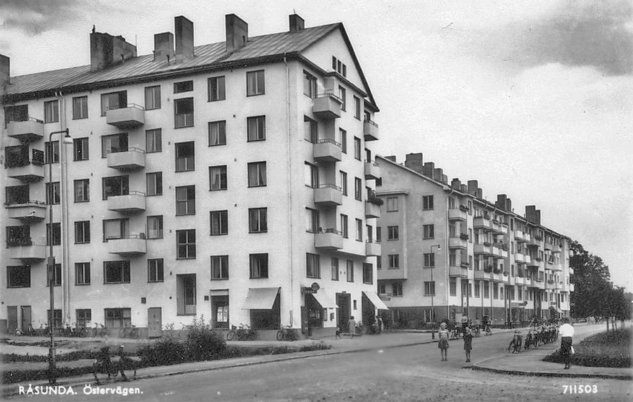 Östervägen i Råsunda, historiskt vykort. Funkishus med balkonger, butiker i bottenvåningen och cyklar längs trottoaren. Bild från Solna stadsbild / Kulturhotell.